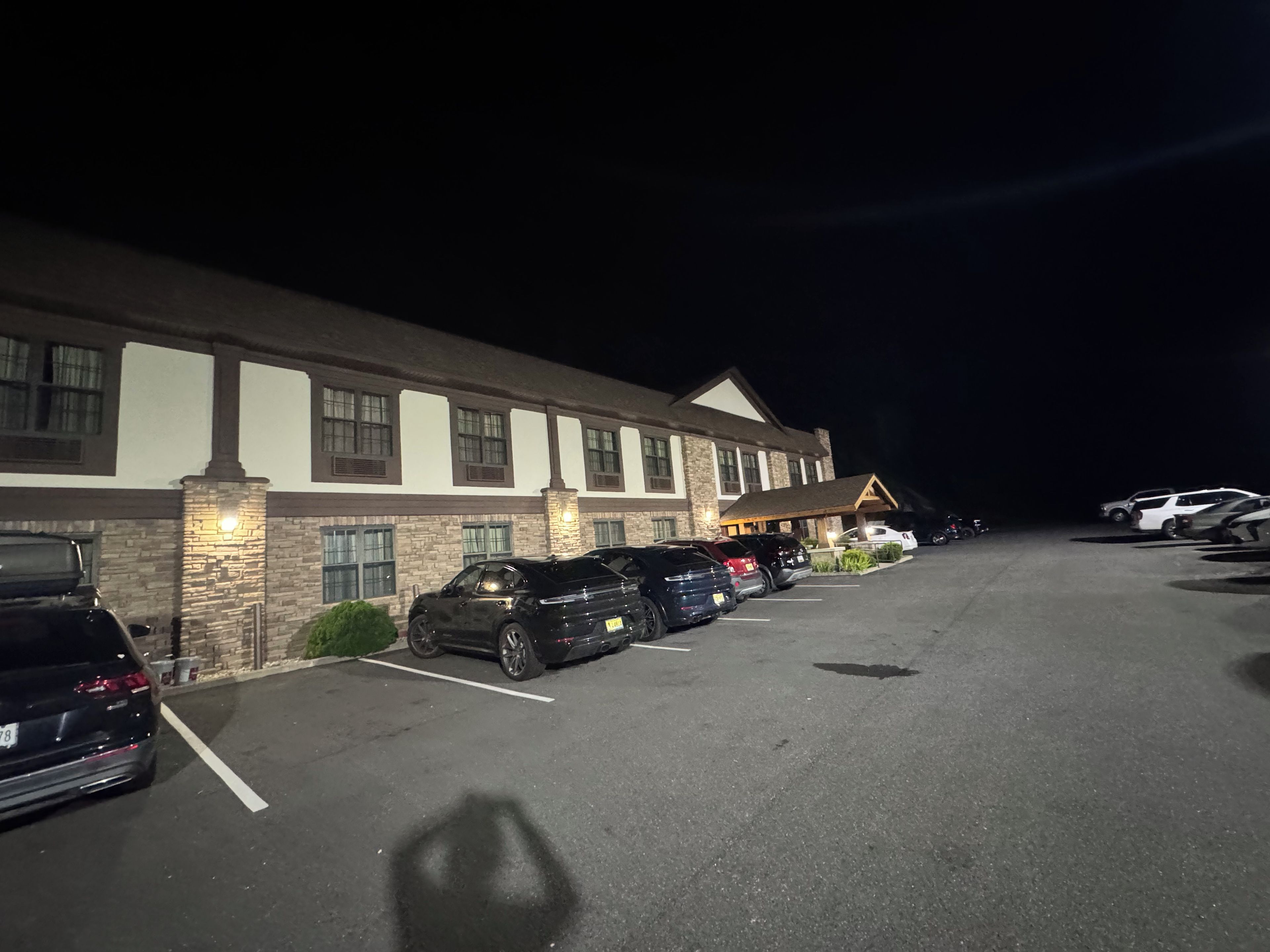 Un hotel con una fila de coches aparcados y un edificio de múltiples ventanas y fachada de piedra.
