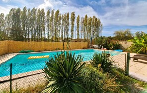 Ein Swimmingpool, umgeben von einer Bambusumzäunung, mit blauem Himmel darüber.