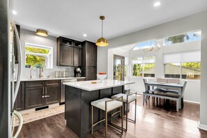 Una cocina moderna con armarios oscuros, una isla central y un comedor con vistas.