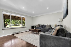 Un salon avec une grande fenêtre, un canapé, une table basse et une lampe.