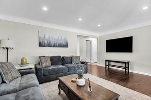 Una sala de estar moderna con un sofá modular, una mesa de centro y un televisor de pantalla plana montado en la pared.