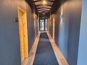 A hallway with wooden doors, a carpeted floor, and a ceiling with exposed beams. - Hotel Boutique 501 (Los Angeles)