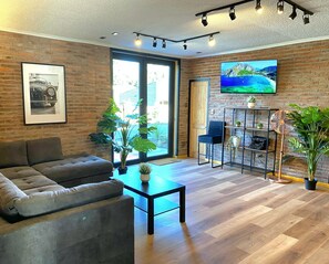 Una sala de estar moderna con un sofá, una mesa de centro y un televisor montado en la pared.