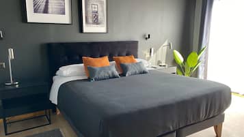 A modern bedroom with a large bed, a nightstand, a lamp, and framed pictures on the wall.