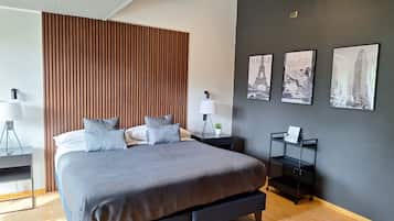Une chambre moderne avec un grand lit, une tête de lit en lattes de bois et trois tableaux encadrés accrochés au mur.