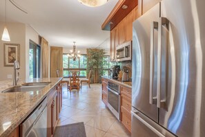A modern kitchen with a central island, stainless steel appliances, and wooden cabinetry. - 160 Steps from kitchen sink to sand! Platinum Interior. 1431sf - New Ownership! (Lahaina)