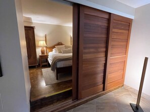 Ein Schlafzimmer mit einem Bett, einem Nachttisch, einer Lampe und einem Holzschrank.