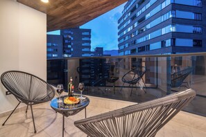Un balcon avec deux chaises, une table et une bouteille de vin.
