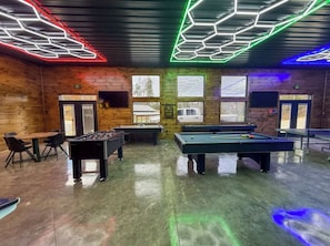 A recreational area with pool tables, foosball, and a billiards table.