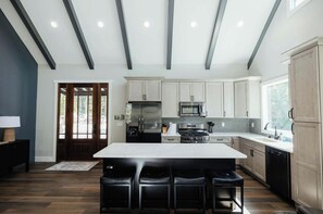 A modern kitchen with a central island, stainless steel appliances, and a herringbone tile backsplash.
