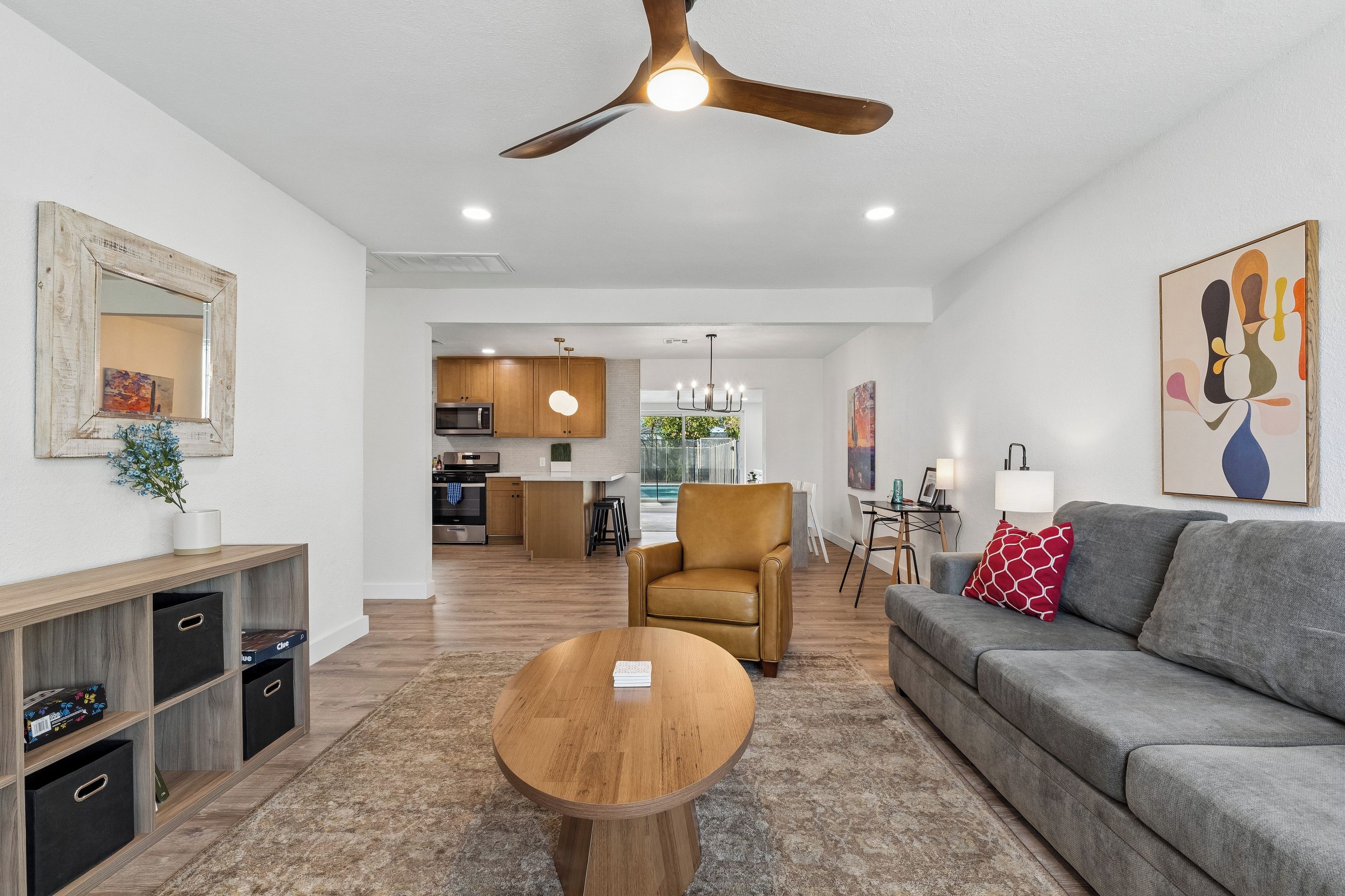 A modern living room with a ceiling fan, a sofa, a coffee table, and a dining area in the background.