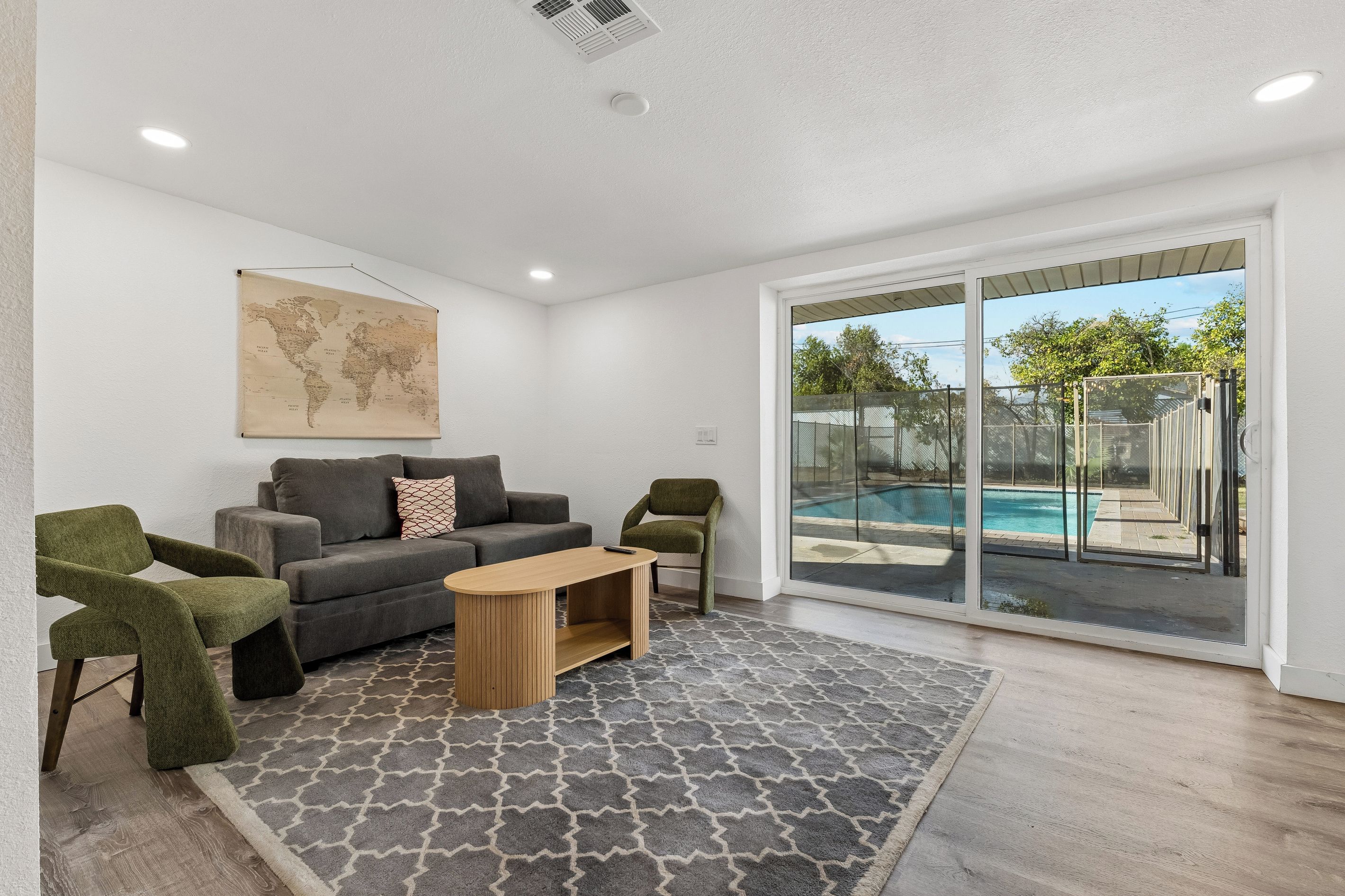 A modern living room with a grey patterned rug, a grey sofa, a wooden coffee table, and a green armchair.