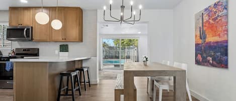A modern kitchen with wooden cabinets, a built-in microwave, and a bar area with stools.