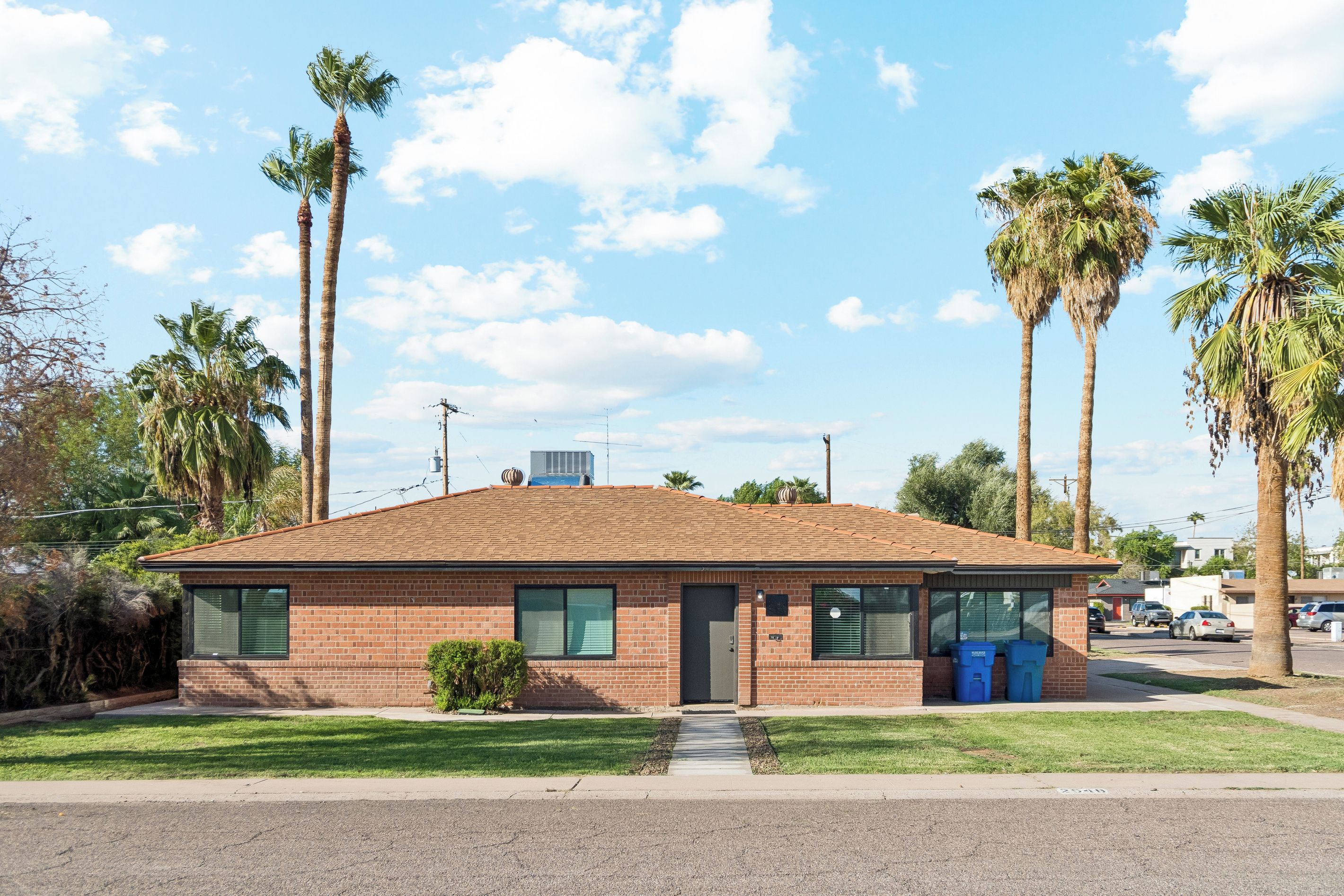 A single-story brick building with a flat roof, a small front porch, and a clear sky.