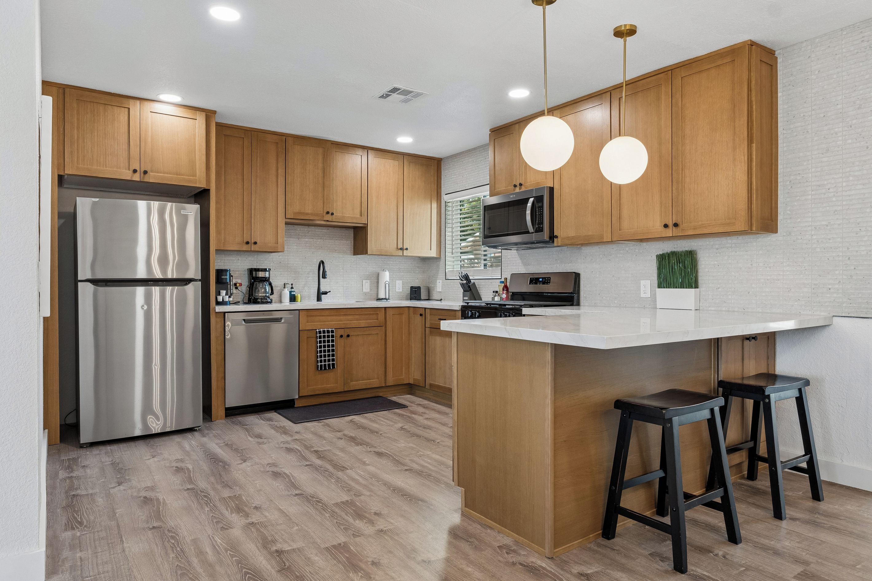 A modern kitchen with wooden cabinets, stainless steel appliances, and a central island with bar stools.
