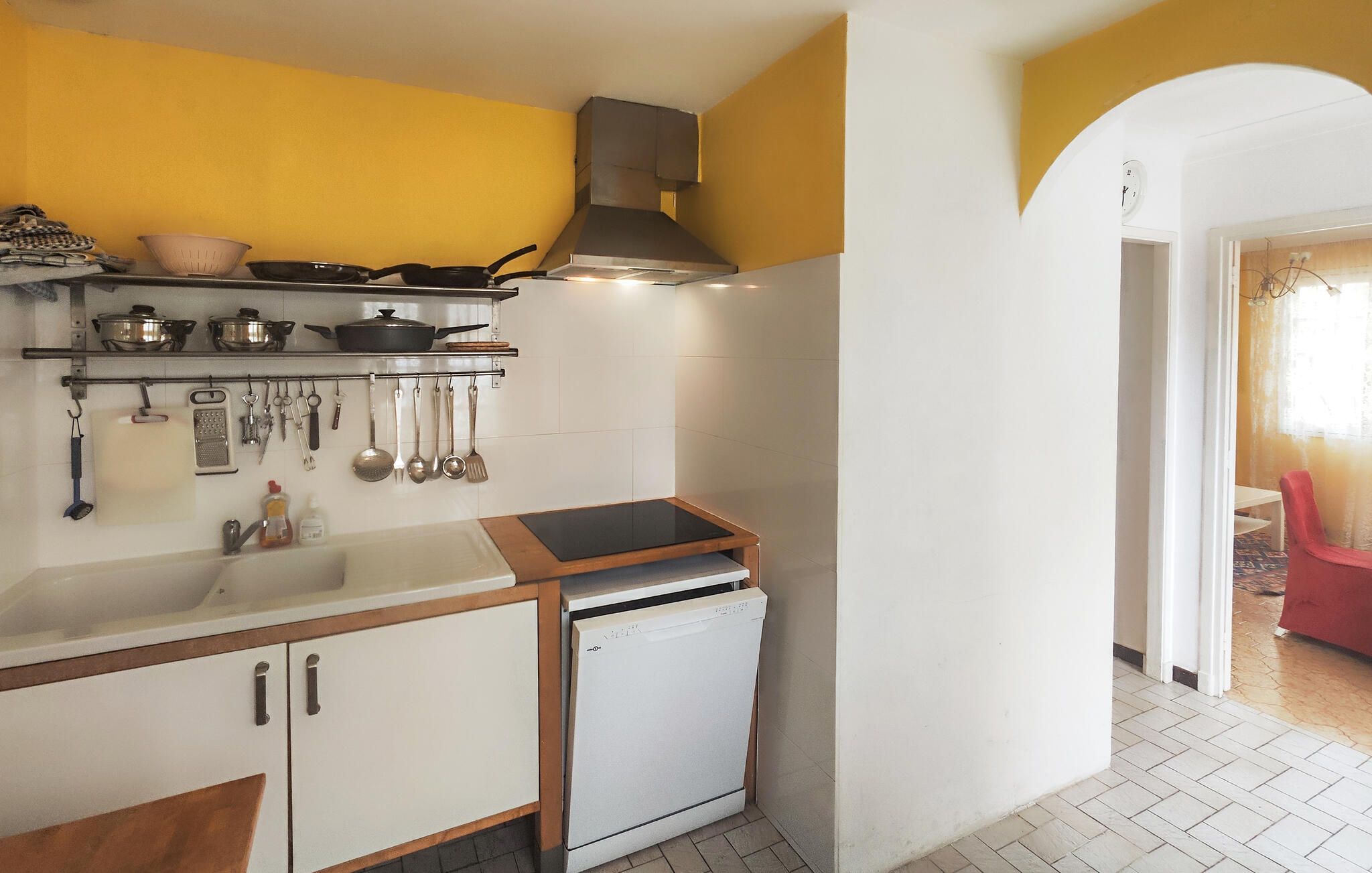 Een kleine keuken met witte kasten, een geïntegreerde vaatwasser en een fornuis.
