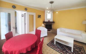 A living room with a fireplace, a white sofa, a red table, and a patterned rug. - Beautiful home in Valras Plage with WiFi (Valras Plage)
