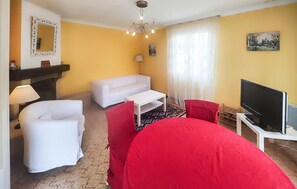 A living room with a sofa, a red chair, a coffee table, a TV, and a fireplace. - Beautiful home in Valras Plage with WiFi (Valras Plage)