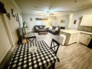 A compact living space with a dining area, a sofa, a kitchen with white cabinets, and a ceiling fan. - Diggs on the River (crystal River)