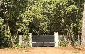 A gated entrance with a metal gate, surrounded by trees and vegetation. - Nice home in Le Val with private swimming pool, can be inside or outside (Le Val)