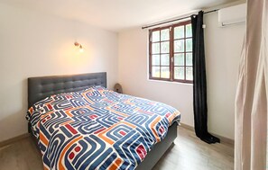 A bedroom with a bed, a window with curtains, and a wall-mounted light fixture. - Nice home in Le Val with private swimming pool, can be inside or outside (Le Val)