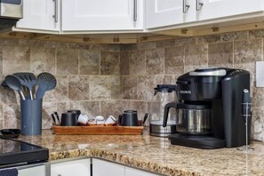 Une cuisine équipée d’une machine à café, d’une bouilloire et d’un plateau contenant des ustensiles.