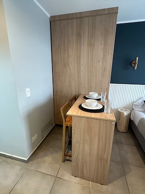 A compact kitchenette with a wooden table, two chairs, and a small countertop. - Monoambiente céntrico sobre calle Mitre (San Carlos de Bariloche)