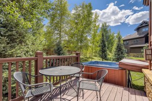 A wooden deck with a hot tub, a table, and chairs. - Beautiful 3 Bedroom + Den Townhome in Breckenridge, Colorado (Breckenridge)