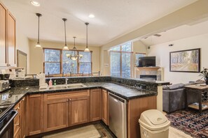 A modern kitchen with a built-in dishwasher, wooden cabinets, a granite countertop, and pendant lighting. - Beautiful 3 Bedroom + Den Townhome in Breckenridge, Colorado (Breckenridge)