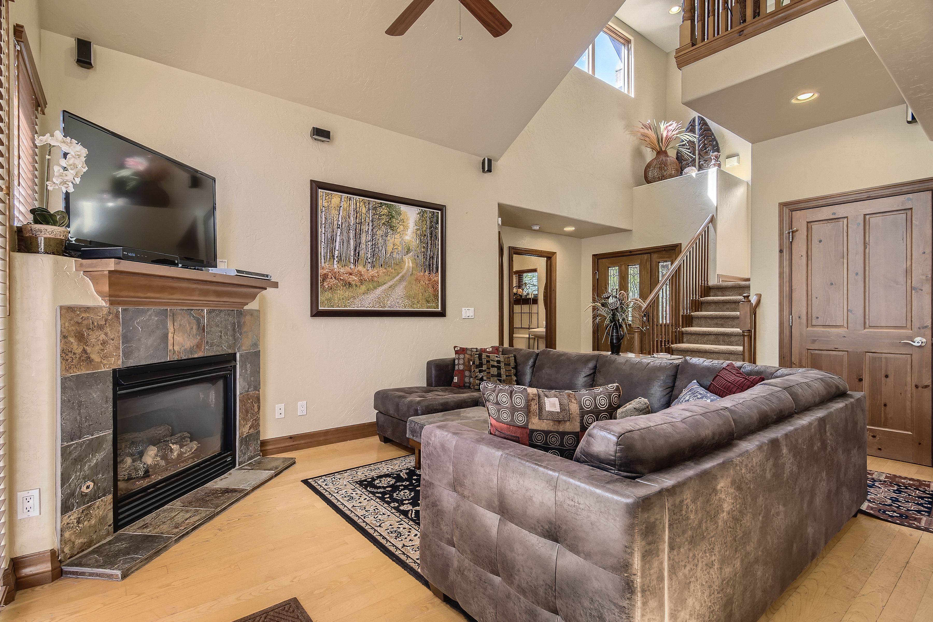 A spacious living room with a fireplace, a large sectional sofa, and a flat-screen TV mounted above it.