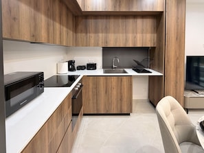 A modern kitchen with wooden cabinets, a microwave, a coffee maker, and a sink.