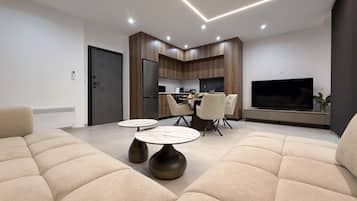 A modern living room with a sofa, a dining table, and a kitchen area with a TV.