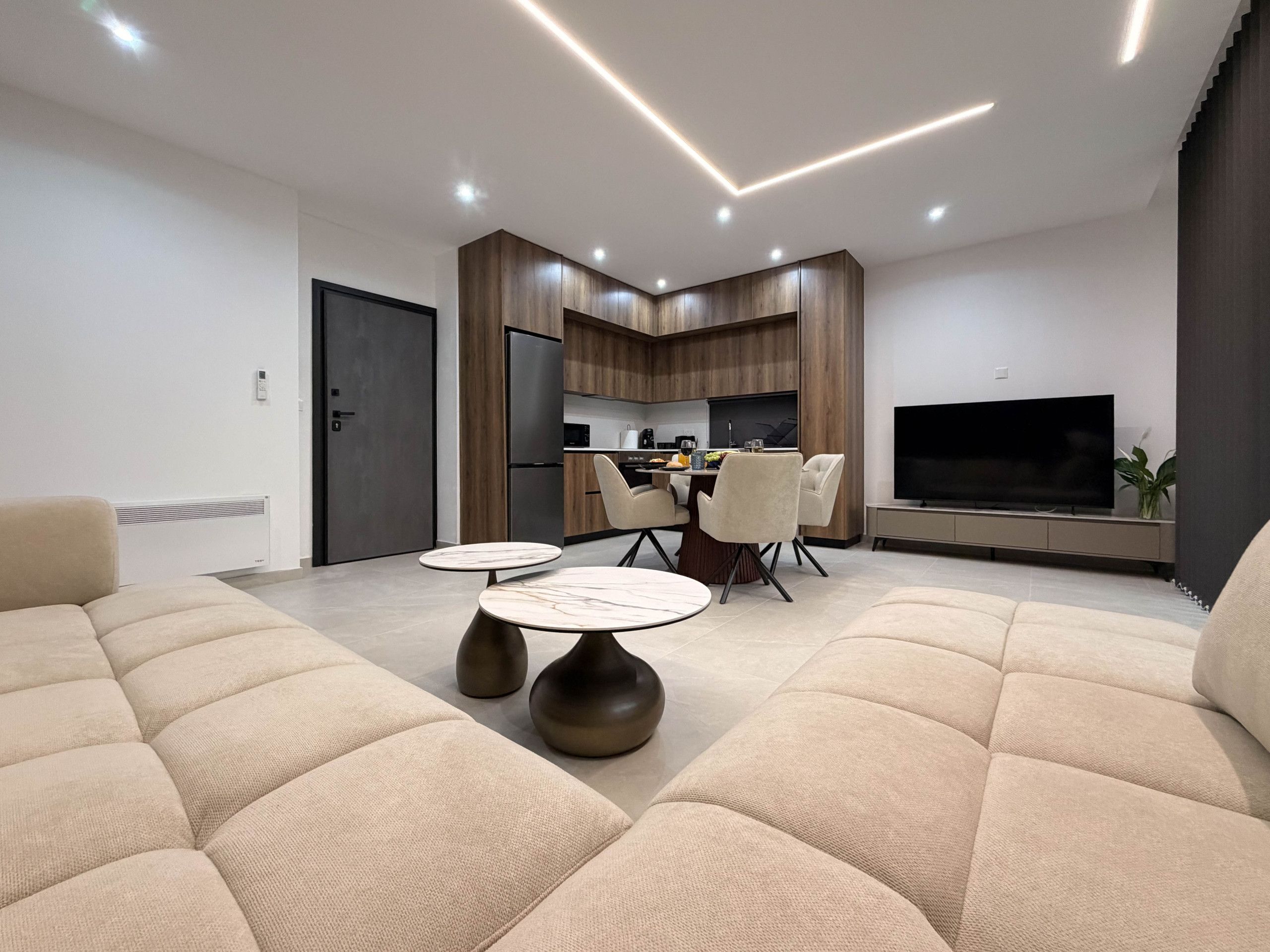 Una sala moderna con un sofá, una mesa de comedor y una zona de cocina con un televisor.