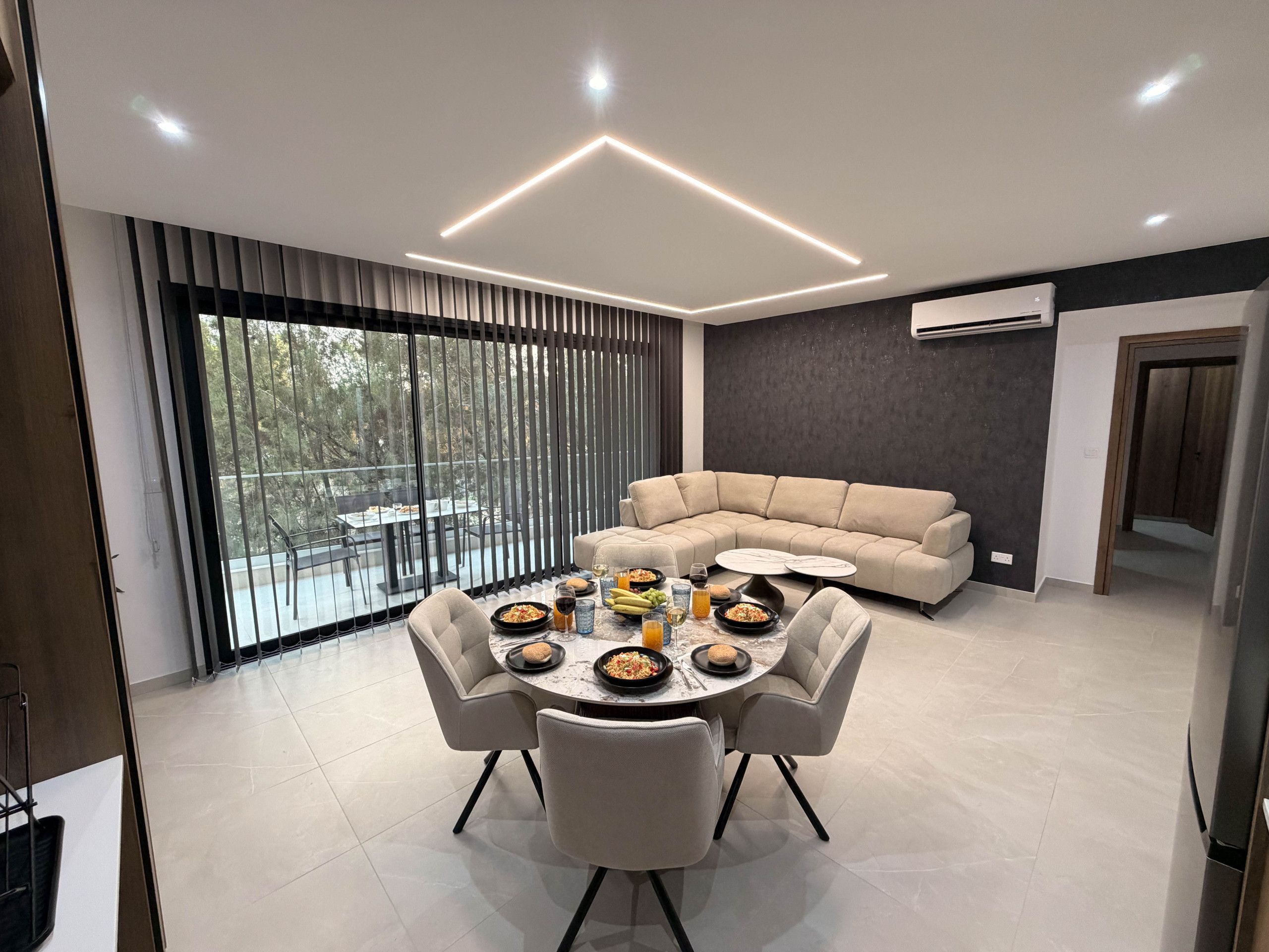A modern dining area with a round table, chairs, and a sofa.
