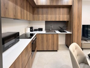 A modern kitchen with wooden cabinets, a microwave, a coffee maker, and a sink.