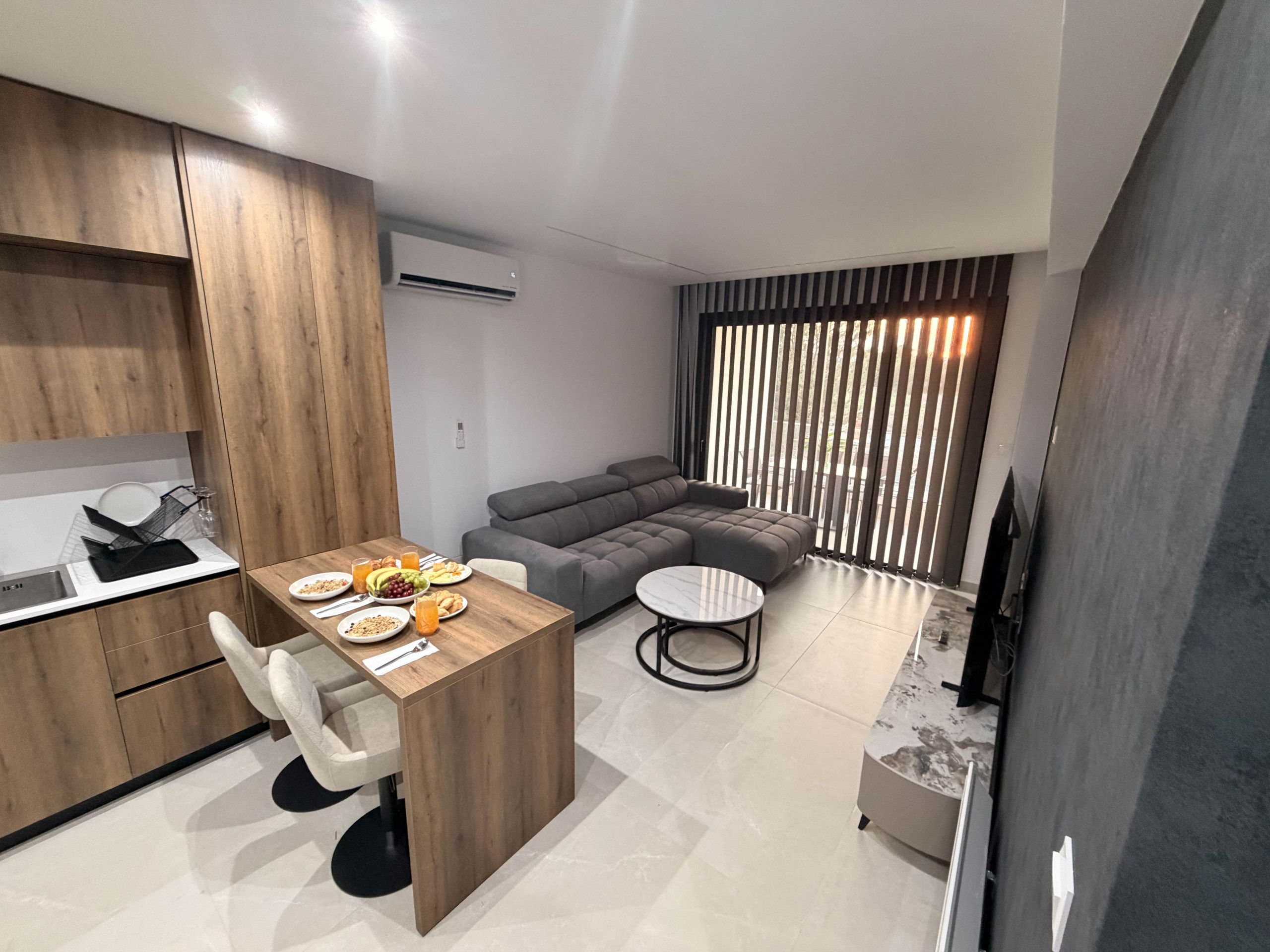 A modern living space with a dining area, a sofa, and a TV.