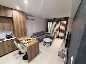 A modern living space with a dining area, a sofa, and a TV. - Cecilia Suite #202 - 1BDR - 24/7 Concierge (Lakatamia)