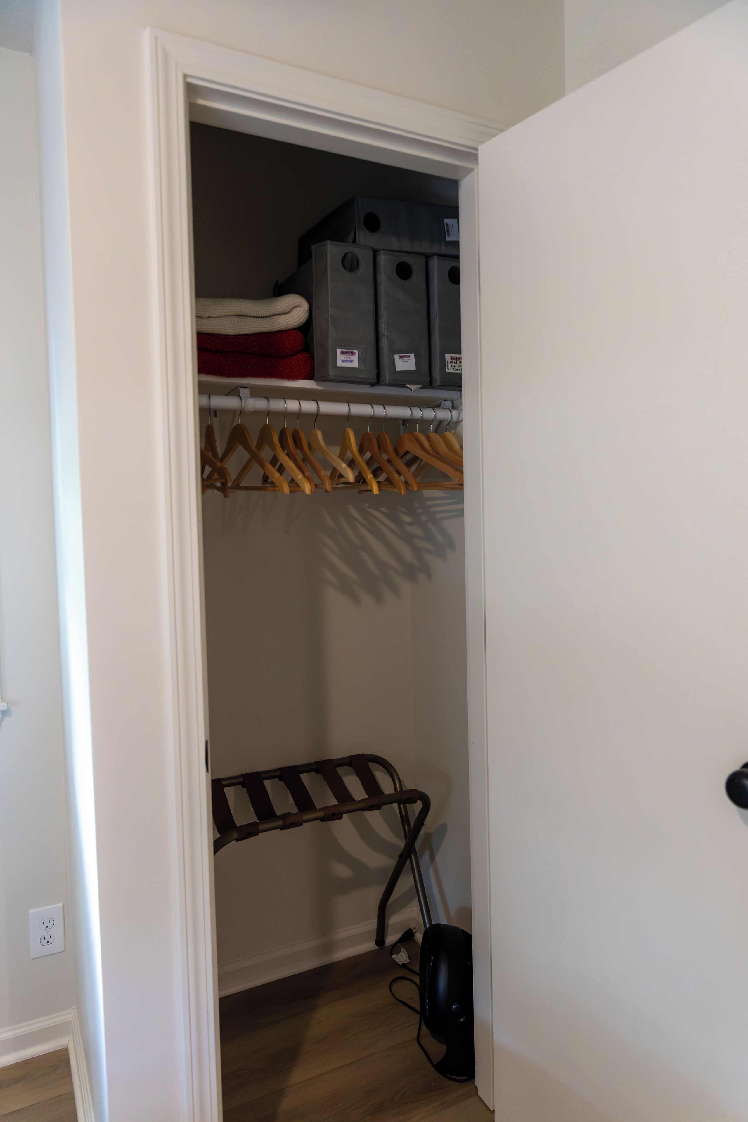 A closet with hanging clothes, storage bins, and a drying rack.