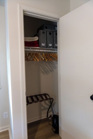 A closet with hanging clothes, storage bins, and a drying rack. - Stylish Ranch -Wooded Lot in North Indianapolis (Indianapolis)