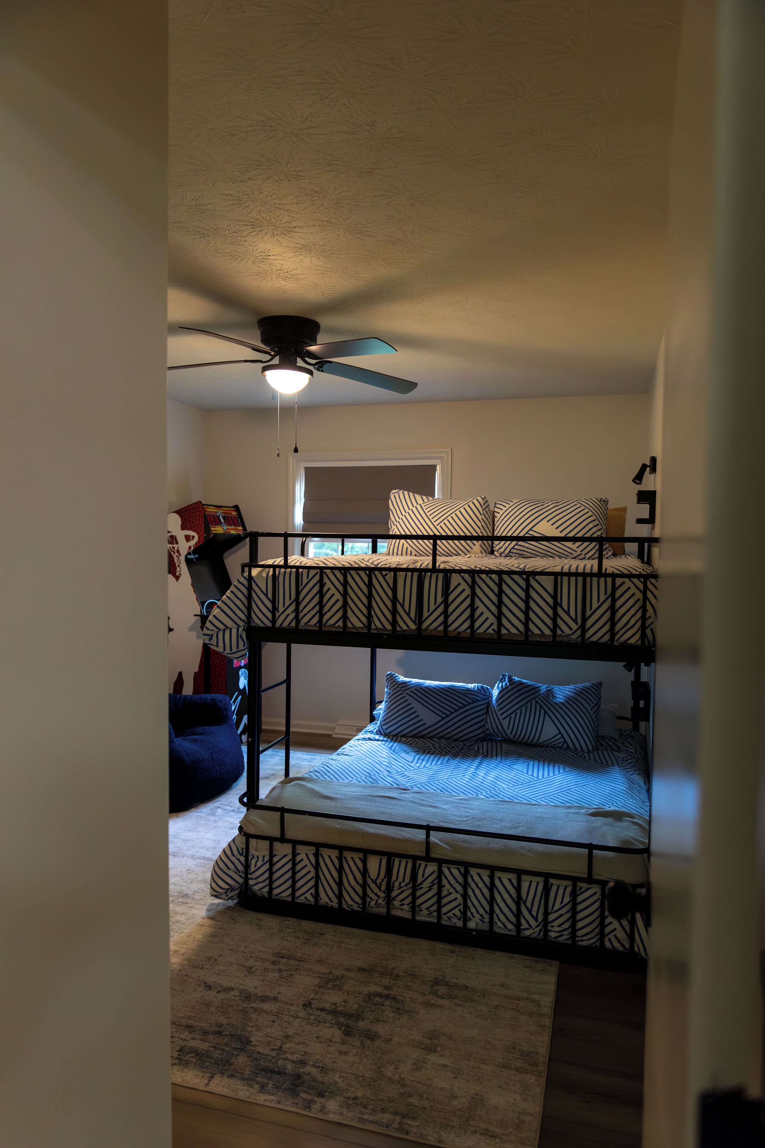 A bunk bed with a ceiling fan and a window with blinds.