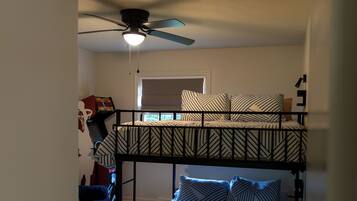 A bunk bed with a ceiling fan and a window with blinds.