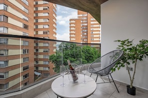 A balcony with a table, two wine glasses, and a bottle of wine. - Brand New Luxury Apartment with AC (Medellín)
