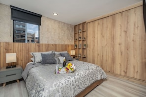 A modern bedroom with a large bed, bedside tables, a wooden wardrobe, and a window with blinds. - Brand New Luxury Apartment with AC (Medellín)