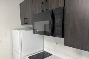 Cozinha equipada com micro-ondas embutido, frigorífico branco e fogão.