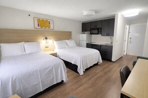 Une chambre d’hôtel avec deux lits, une kitchenette et un coin repas.