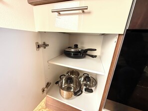 A kitchen cabinet with a pot rack, including a frying pan and several pots. - Comfortable and worry-free living (Hofheim)