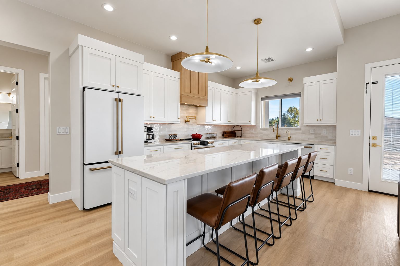 A modern kitchen with white cabinetry, a large island with bar stools, and pendant lighting.