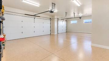 Un garage spacieux avec une grande porte blanche, un éclairage au plafond et une vue dégagée sur l’extérieur grâce à une fenêtre.