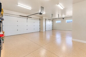 A spacious garage with a large white door, overhead lighting, and a clear view of the outside through a window. - Modern 3BR Home with Fenced Yard Near Zion & Dunes (Colorado City)