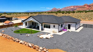 A modern house with a large patio, a swimming pool, and a view of mountains. - Modern 3BR Home with Fenced Yard Near Zion & Dunes (Colorado City)